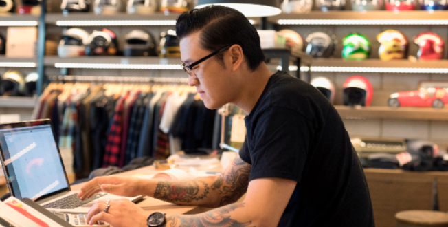 Motorcycle shop owner working at laptop behind counter